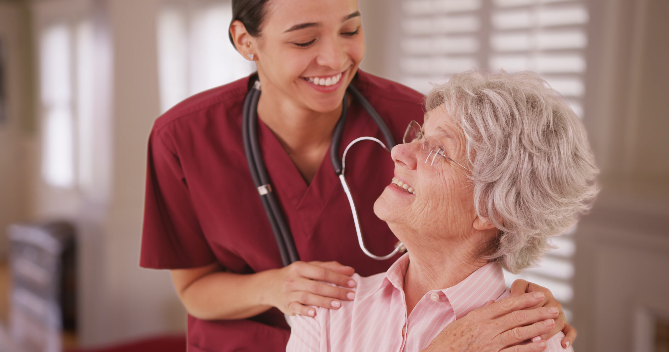 Hispanic,Female,Nurse,Looking,And,Smiling,With,Senior,Caucasian,Woman