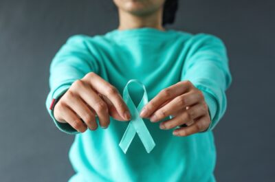 Close-up,Teal,Awareness,Ribbon,Holded,By,Woman,Hands,To,Support